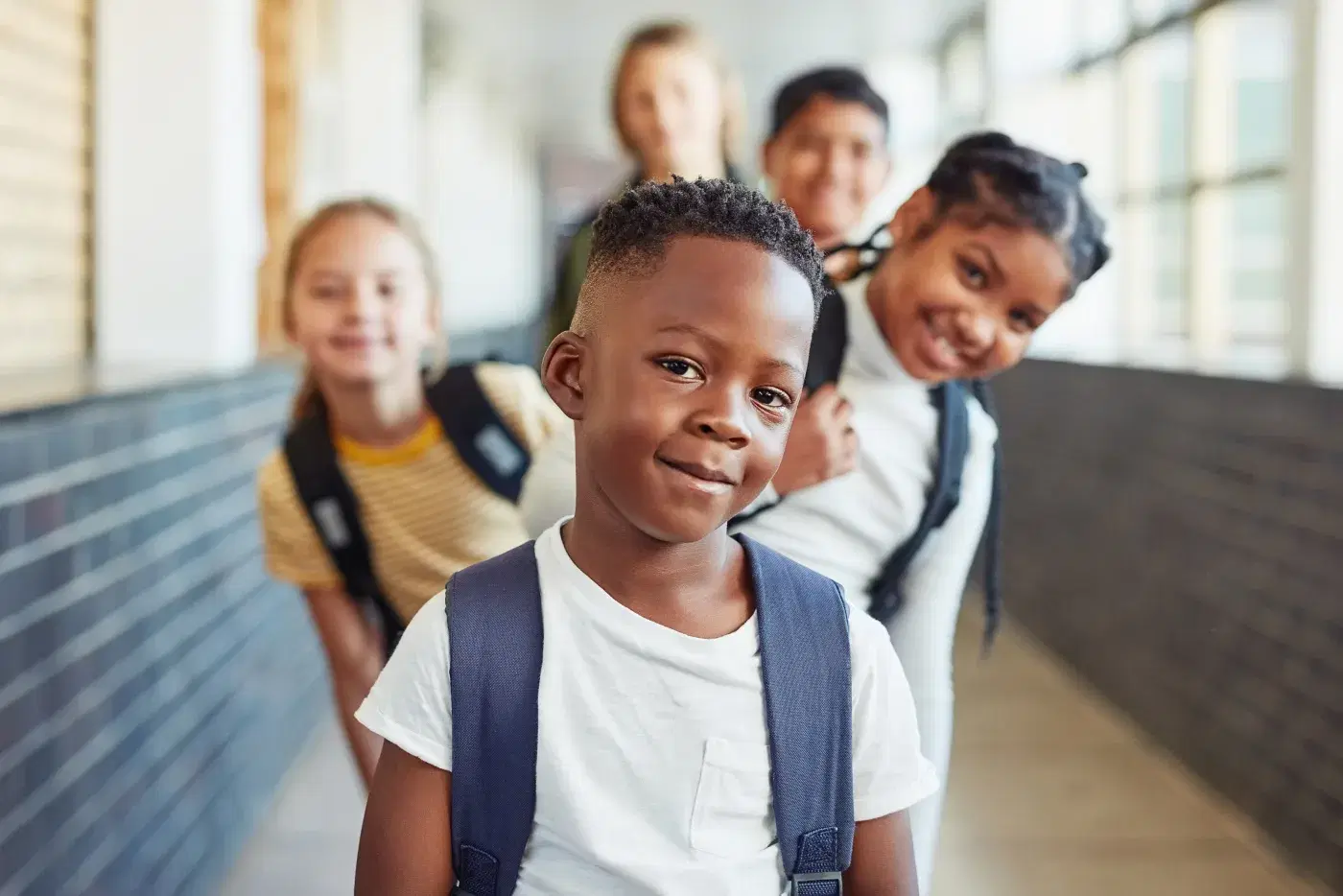 Estudantes em fila no corredor da escola, o primeiro olhando para a câmera