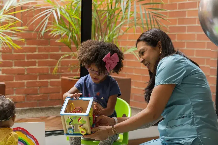 Terapeuta e duas estudantes em um atendimento com brinquedo pedagógico.