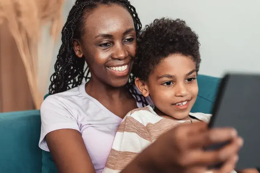 Mãe e filho no sofá olhando juntos a tela de um tablet.